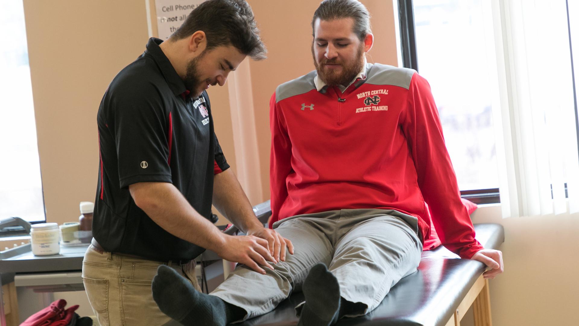 Athletic training student examining patient's knee