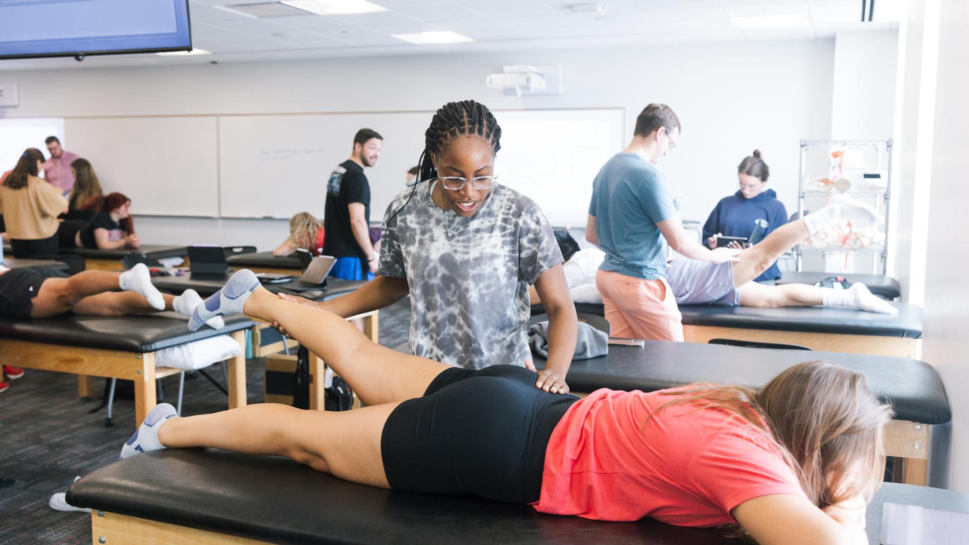 Athletic training student lifting patient's leg