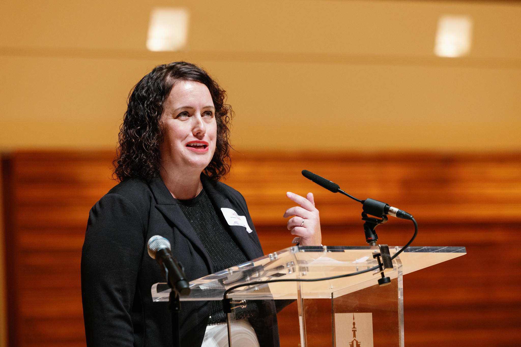 A woman standing and speaking on the stage of the Wentz Concert Hall.