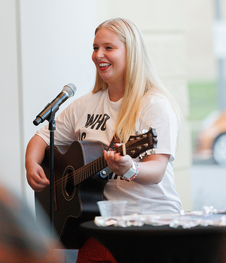 A North Central College student playing a guitar.