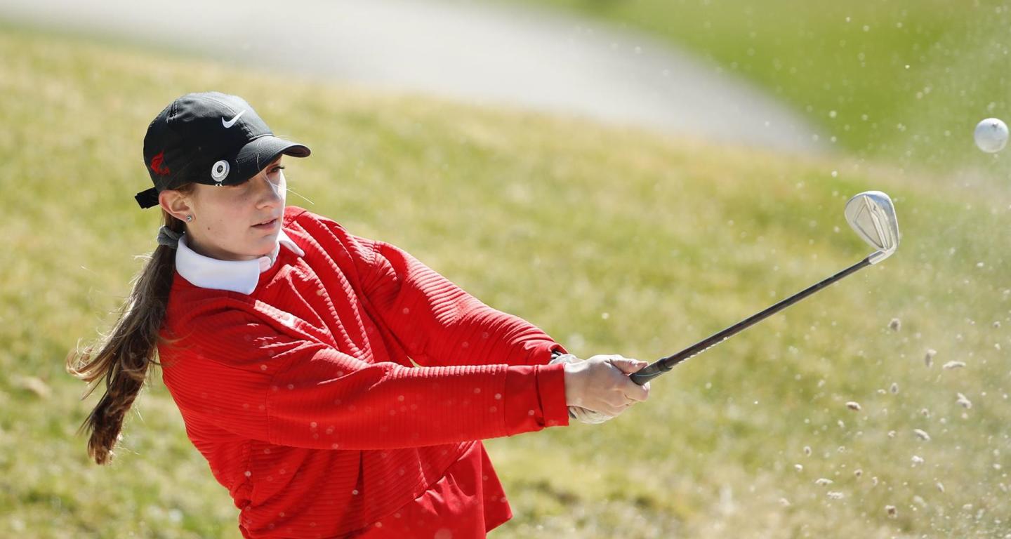 A member of the North Central College women's golf team hits a shot out of a sand trap.