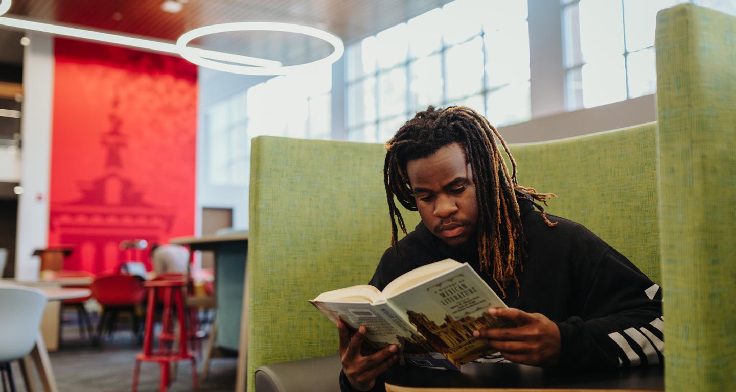 A North Central College student with a textbook.