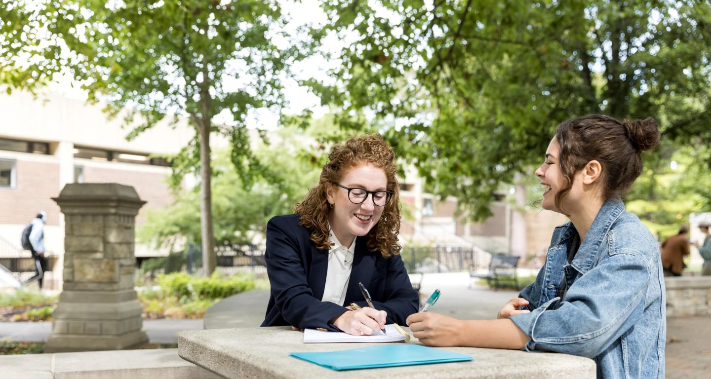 A North Central College professor and student sitting at a table and laughing.