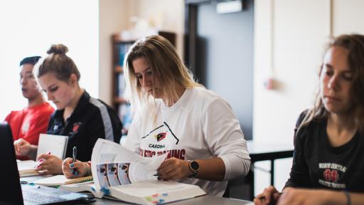 Three North Central College students looking through want ads.